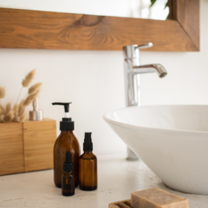 Badezimmer Impression - Waschbecken - Boho Stil mit Holz und braunen Glasflschen sowie Pampasgras im Hintergrund